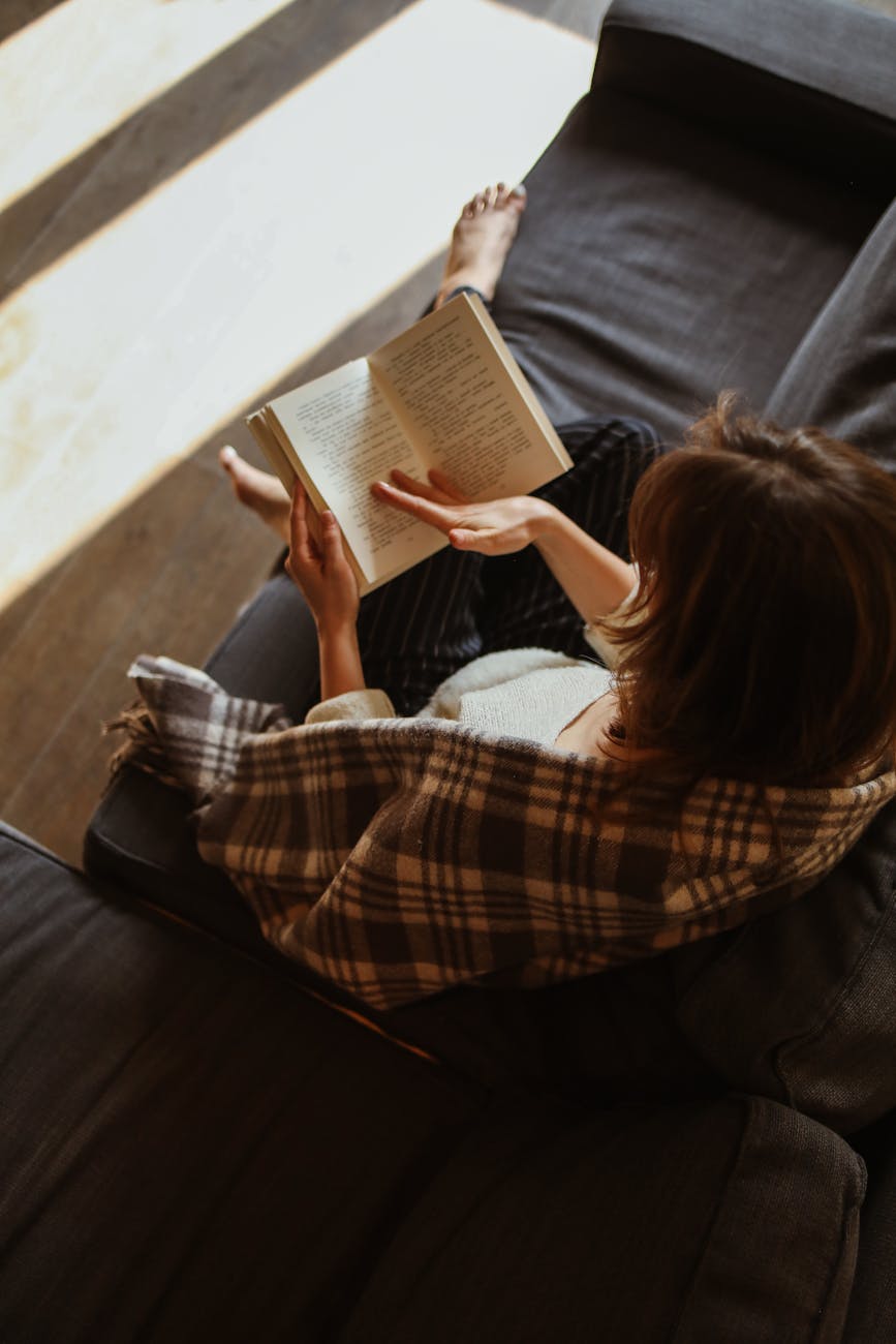 woman sitting on a sofa and reading a book