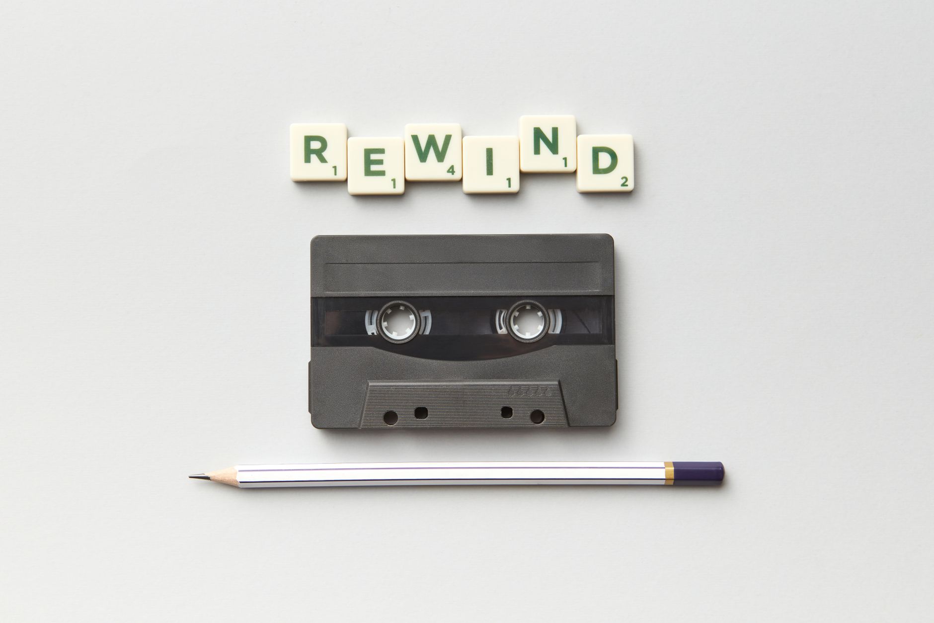 a cassette a pen and the word rewind from scrabble letter tiles